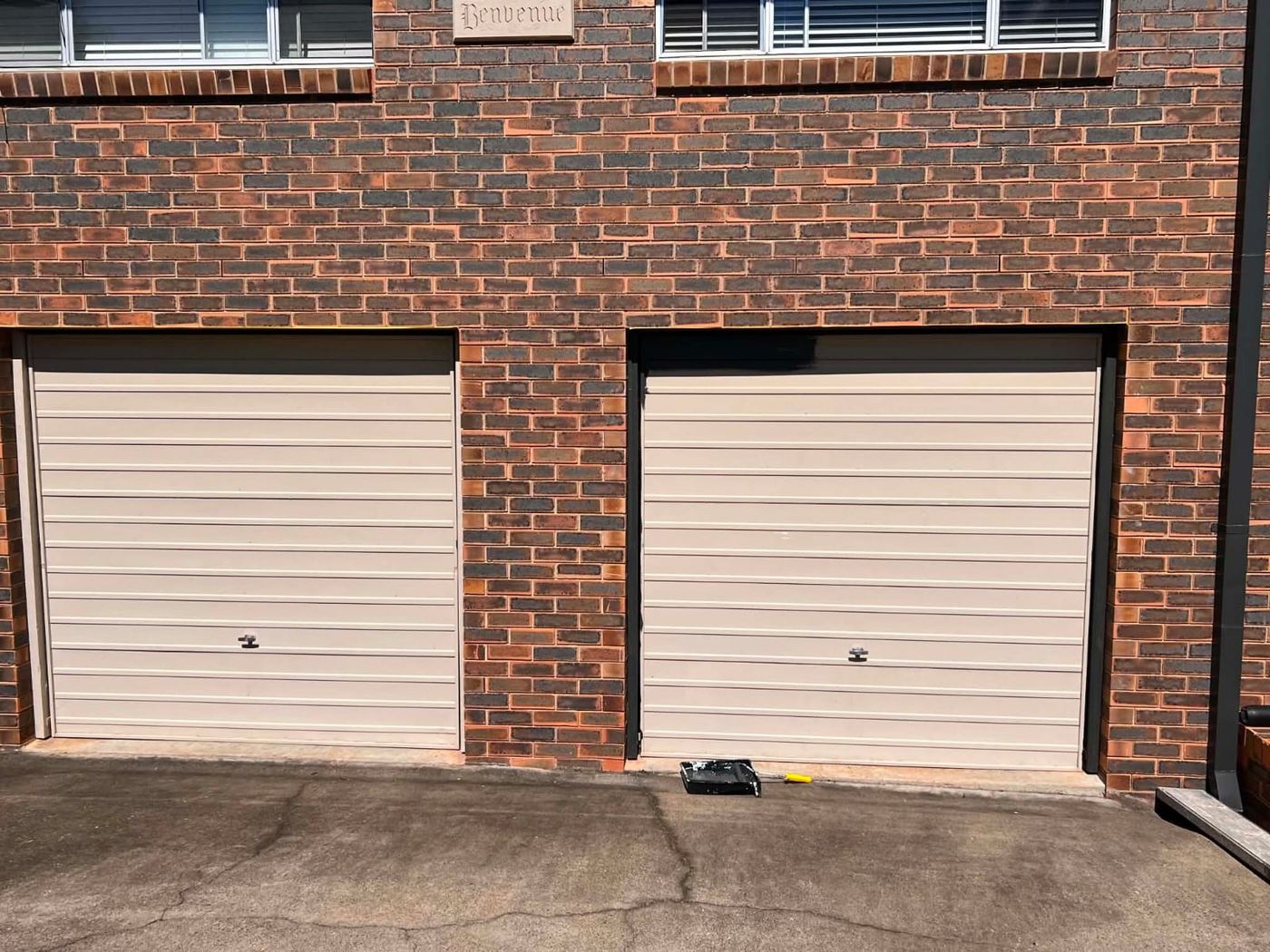 Brick home garage doors in beige before repaint